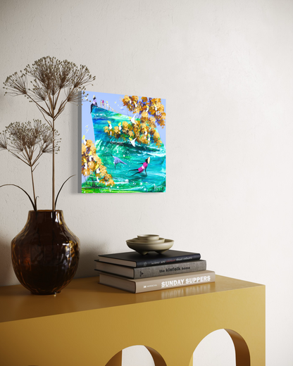 Side view of When You’re Ready by Adam Bogusz, 30 x 30 cm MDF board, showing the painted edge as it hangs on a white wall above a mustard yellow console table with an amber glass vase of dried stems and a stack of books topped with a ceramic bowl.
