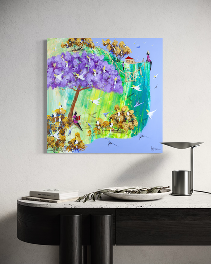Just a Story by Adam Bogusz, 50 x 50 cm painting on MDF board hanging above a black console with a travertine top, a stone bowl holding an olive branch, books and a metal lamp, showing a purple jacaranda full of cockatoos and a girl reading beneath it.