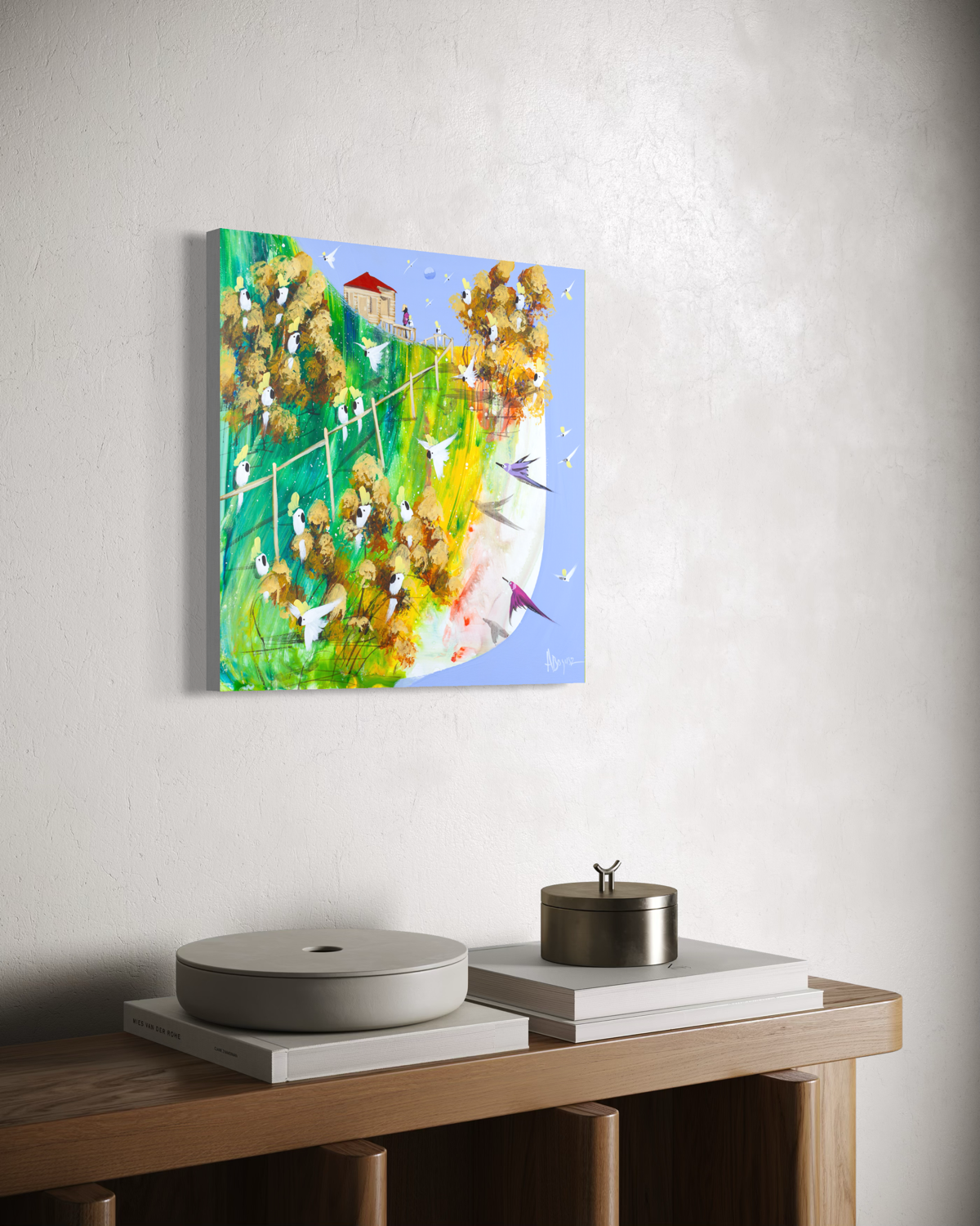 What Stays by Adam Bogusz hanging unframed on a pale wall above a timber console with books and lidded vessels, seen at a slight angle so the depth of the painted board is visible.