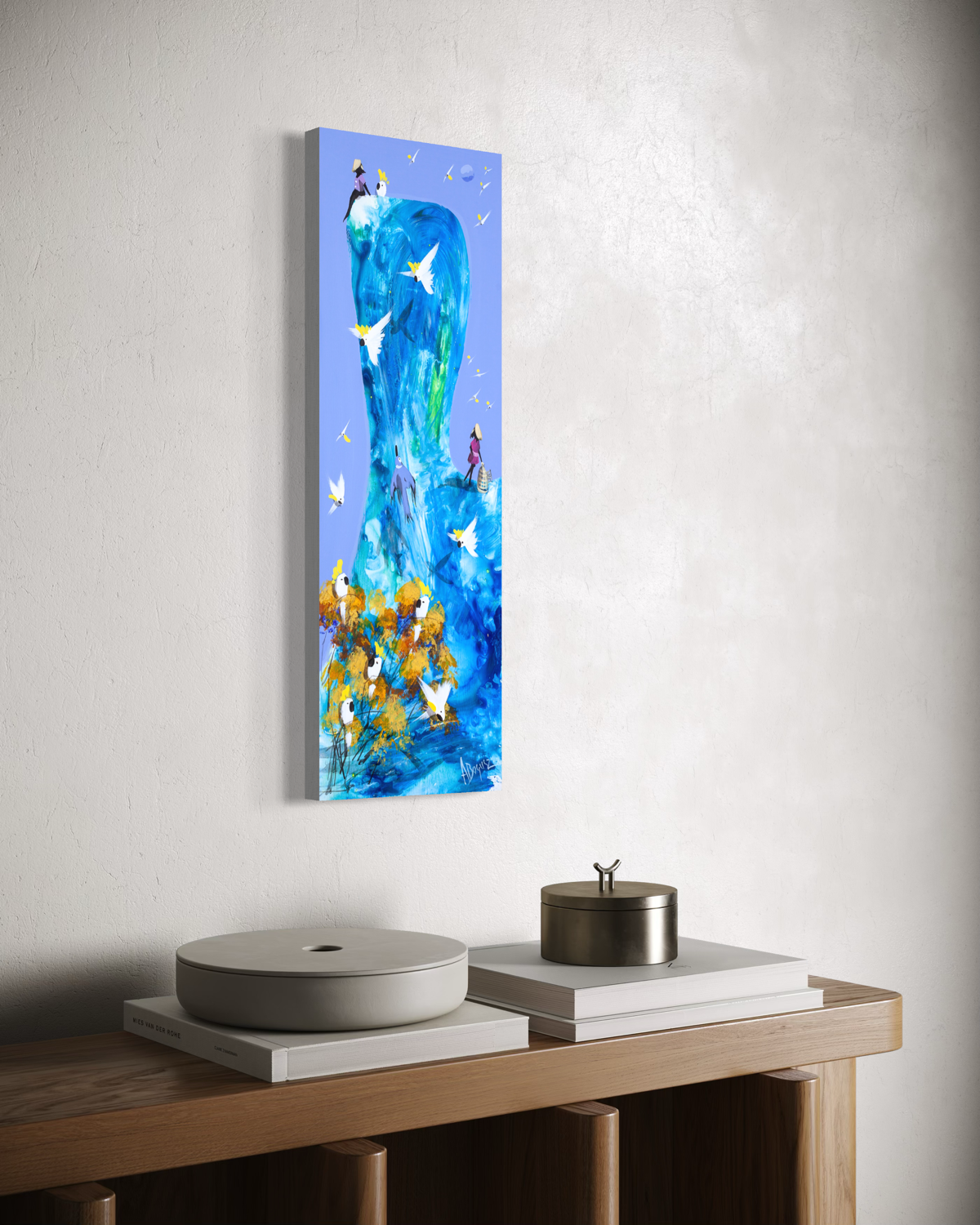 The Same Blue by Adam Bogusz hanging unframed on a pale textured wall above a timber console with books and lidded vessels, seen at a slight angle so the depth of the painted board is visible.