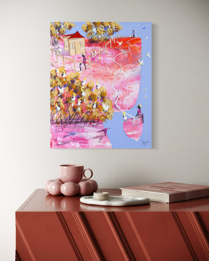 Still Holding On by Adam Bogusz shown hanging on a wall above a red sideboard, styled with books and a candle, to indicate scale in a room.