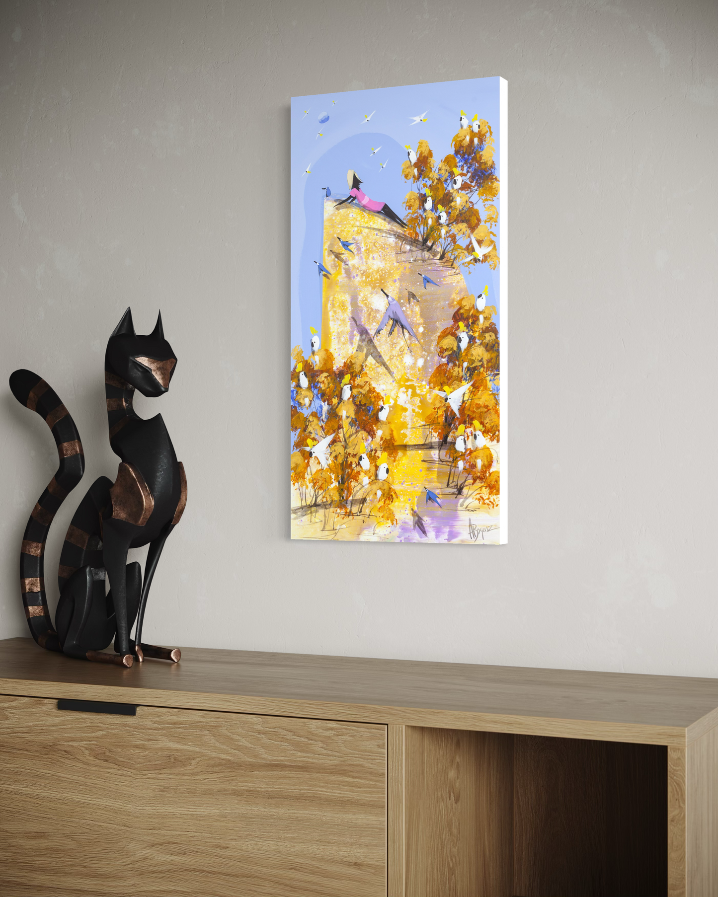 Nowhere to Be by Adam Bogusz hanging unframed on a neutral wall above an oak cabinet, seen at a slight angle so the depth of the painted board is visible, with a black cat sculpture to the left.
