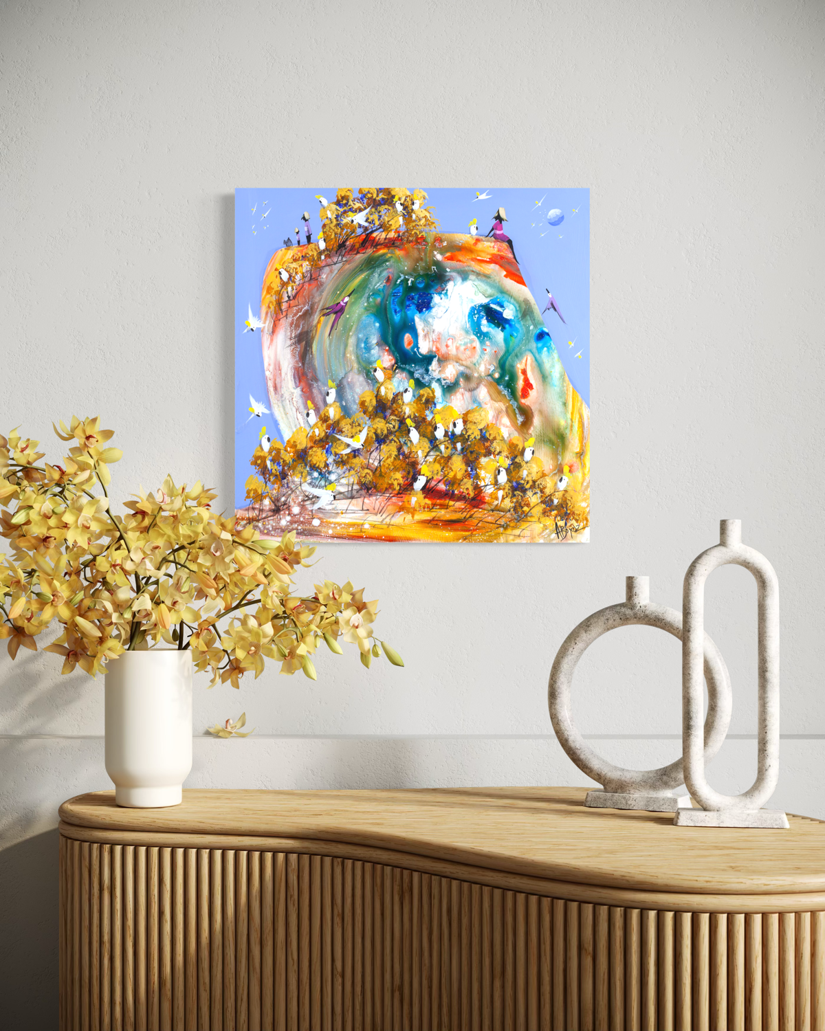 Just for a Moment by Adam Bogusz displayed on a pale wall above a fluted timber sideboard styled with yellow orchids in a white vase and two stone sculptures, shown to indicate scale.