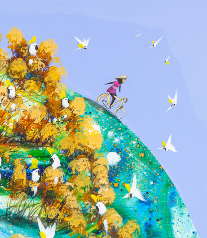 Detail of Freewheeling showing the woman in pink riding along the top of the green hill with her hands off the handlebars, cockatoos in golden trees below her and white birds crossing the pale blue sky.