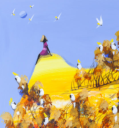 Detail of Always There by Adam Bogusz, showing a woman in pink seated on the tip of a yellow hill against a light blue sky, with a pale moon and small white cockatoos in flight around her.